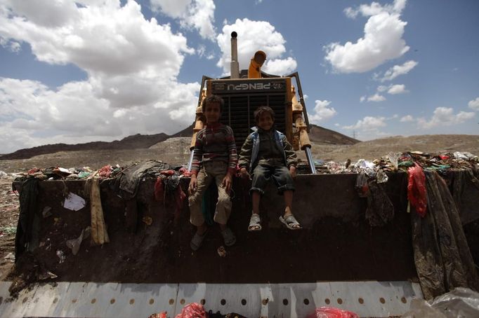 Boys sit on a bulldozer at a garbage disposal site near Sanaa