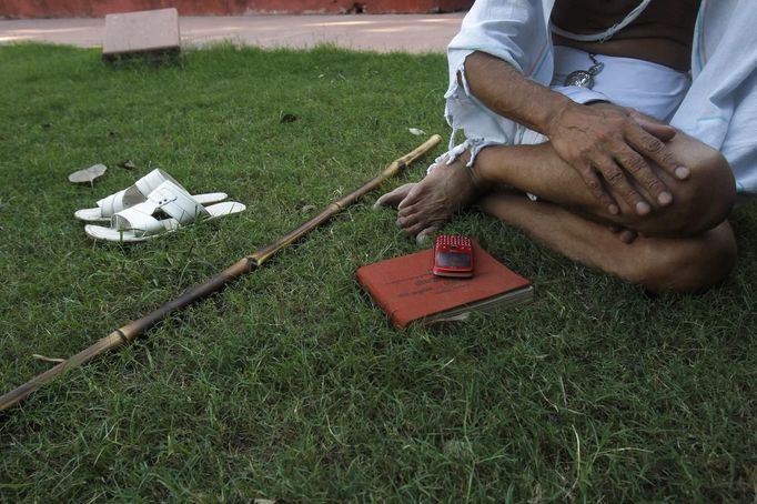 Mahesh Chaturvedi, 63, who dresses up like Mahatma Gandhi, sits next to a copy of the Bhagavad-Gita, one of Hinduism's most holy books, at a park in New Delhi September 28, 2012. Chaturvedi says that the soul of Gandhi resides in him and he has been sent to continue the work of Father of the Nation. After his self proclaimed transformation in 2002 as Gandhi, Chaturvedi has been travelling extensively and plays up to his startling resemblance to Gandhi at protests and demonstrations. Picture taken September 28, 2012. REUTERS/Mansi Thapliyal (INDIA - Tags: SOCIETY) Published: Lis. 26, 2012, 3:59 dop.