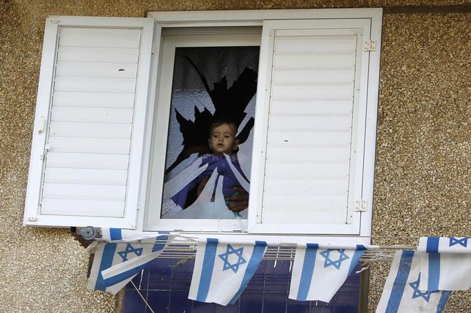 A baby is seen at a broken window after a rocket fired by Palestinian militants in Gaza hit a house in the southern town of Netivot November 12, 2012. The Palestinian rocket fired from the Gaza Strip struck the house in southern Israel on Monday, causing damage but no injuries, and Israeli officials quickly warned of a tough response to the latest surge in violence. REUTERS/Amir Cohen (ISRAEL - Tags: POLITICS CIVIL UNREST) Published: Lis. 12, 2012, 9:21 dop.