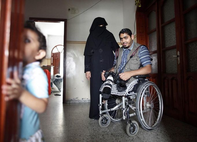 Wheelchair-bound Palestinian freelance photographer Moamen Qreiqea holds his cameras next to his mother in his home in Gaza City October 1, 2012. Qreiqea, 25, lost both his legs in an Israeli air strike in 2008 while taking pictures east of Gaza. The father of two is determined to continue his career despite his disability. REUTERS/Suhaib Salem (GAZA - Tags: MEDIA SOCIETY) Published: Říj. 1, 2012, 3:39 odp.