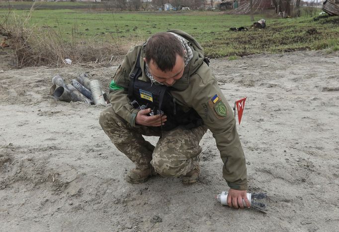 Ženista ve městě Motyžyn nedaleko Kyjeva zvedá nevybuchlou část kazetové bomby, která se před dopadem na zem rozpadne na velké množství menších bomb.