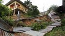 A resident of Mount Pleasant Road, Carenage, about 10 km (6 miles) west of the capital Port of Spain, walks past a broken fence along a road damaged by heavy rainfall due to the passing of Tropical Storm Isaac August 23, 2012. Tropical Storm Isaac unleashed heavy rain and winds off Puerto Rico and the Virgin Islands as it moved across the Caribbean on Thursday and could strengthen into a hurricane before tearing across the Dominican Republic and Haiti. REUTERS/Andrea De Silva (TRINIDAD AND TOBAGO - Tags: DISASTER ENVIRONMENT TPX IMAGES OF THE DAY) Published: Srp. 24, 2012, 1:21 dop.