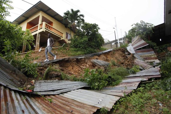 A resident of Mount Pleasant Road, Carenage, about 10 km (6 miles) west of the capital Port of Spain, walks past a broken fence along a road damaged by heavy rainfall due to the passing of Tropical Storm Isaac August 23, 2012. Tropical Storm Isaac unleashed heavy rain and winds off Puerto Rico and the Virgin Islands as it moved across the Caribbean on Thursday and could strengthen into a hurricane before tearing across the Dominican Republic and Haiti. REUTERS/Andrea De Silva (TRINIDAD AND TOBAGO - Tags: DISASTER ENVIRONMENT TPX IMAGES OF THE DAY) Published: Srp. 24, 2012, 1:21 dop.