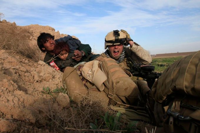 Americký voják Chris Sanderson se snaží překřičit palbu, aby dal pokyny afghánskému muži s dítětem, který se snaží vyhnout se kulkám. Přestřelka se odehrála u obce Marjah v provincii Helmand. 13. únor 2010.