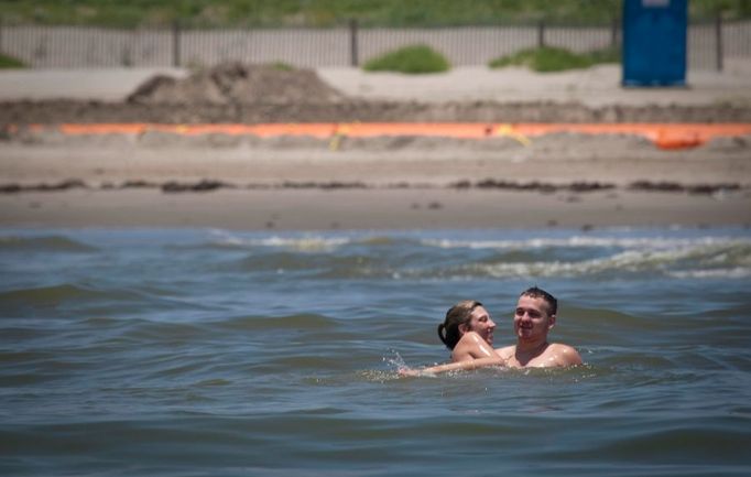 Ani blížící se olejová skvrna neodradila tyto přehřáté turisty od koupele na pláží Grand Isle, stát Lousiana. Oblast znečišťuje unikají ropa z potopené plošiny Deepwater Horizont.