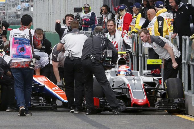 Haas F1 driver Romain Grosjean (R) sits in his car that collided with Manor Racing F1 driver Rio Haryanto at the start of the third practice session at the Australian For