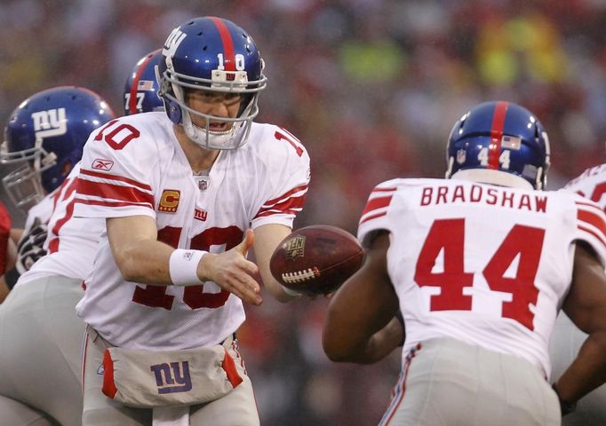 Quarterback Giants Eli Manning předává šišku Ahmadu Bradshawovi