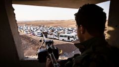 Irácký voják sleduje konvoj uprchlíků z Mosulu.