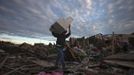 A man carries his belongings through debris after the suburb of Moore, Oklahoma was left devastated by a tornado, on May 21, 2013. Rescuers went building to building in search of victims and survivors picked through the rubble of their shattered homes on Tuesday, a day after a massive tornado tore through the Oklahoma City suburb of Moore, wiping out blocks of houses and killing at least 24 people. REUTERS/Adrees Latif (UNITED STATES - Tags: DISASTER ENVIRONMENT) Published: Kvě. 22, 2013, 2:24 dop.