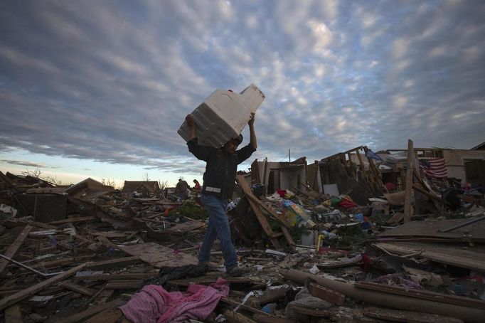 A man carries his belongings through debris after the suburb of Moore, Oklahoma was left devastated by a tornado, on May 21, 2013. Rescuers went building to building in search of victims and survivors picked through the rubble of their shattered homes on Tuesday, a day after a massive tornado tore through the Oklahoma City suburb of Moore, wiping out blocks of houses and killing at least 24 people. REUTERS/Adrees Latif (UNITED STATES - Tags: DISASTER ENVIRONMENT) Published: Kvě. 22, 2013, 2:24 dop.