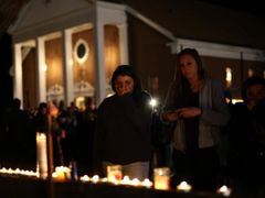 Lidé rozsvěcují svíčky před kostelem v Newtownu, kde v pátek zemřelo rukou střelce 27 lidí, z toho 20 dětí.