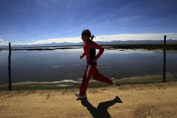 Gladys Tejeda, the first Peruvian athlete who qualified for the 2012 London Olympic Games, runs next to the Chinchaycocha lake during her training in the Andean province of Junin May 14, 2012. A private company will take Gladys' mother Marcelina Pucuhuaranga, 69, to London as part of the "Thank you Mom" program. For Pucuhuaranga, who received her first passport, it will be the first time travelling out of Peru. The program will take about 120 mothers of different athletes around the world to attend the games. Tejeda, the youngest of nine children, returned to her hometown to visit her mother and to focus on training where she will run more than 20 km every day in the highlands (over 4,105 meters above sea level). Picture taken May 14, 2012. REUTERS/Pilar Olivares(PERU - Tags: SPORT ATHLETICS OLYMPICS) Published: Kvě. 17, 2012, 6:12 odp.