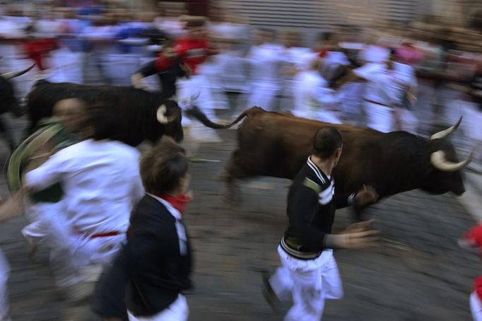 Runners sprint alongside Victoriano del Rio fighting bulls at the Estafeta corner during the sixth running of the bulls at the San Fermin festival in Pamplona July 12, 2012. Several runners suffered light injuries in a run that lasted two minutes and twenty seconds, according to local media. REUTERS/Vincent West (SPAIN - Tags: ANIMALS SOCIETY) Published: Čec. 12, 2012, 8:46 dop.