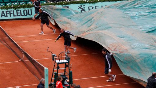 Zaměstnanci zatahují kurt kvůli dešti po přerušení utkání mezi Rafalem Nadalem a Davidem Ferrerem během semifinále French Open 2012.