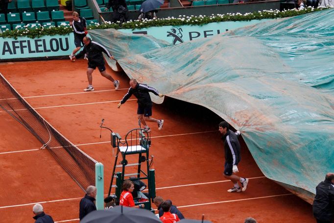 Zaměstnanci zatahují kurt kvůli dešti po přerušení utkání mezi Rafalem Nadalem a Davidem Ferrerem během semifinále French Open 2012.