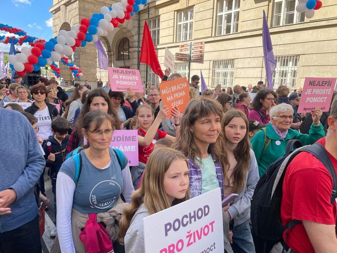 Mezi zhruba několika sty účastníky Pochodu pro život jsou především rodiny s dětmi, lidé mají vlajky s nápisy "Nesoudíme, pomáháme" či "Jsme kreativní, jsme pro život".