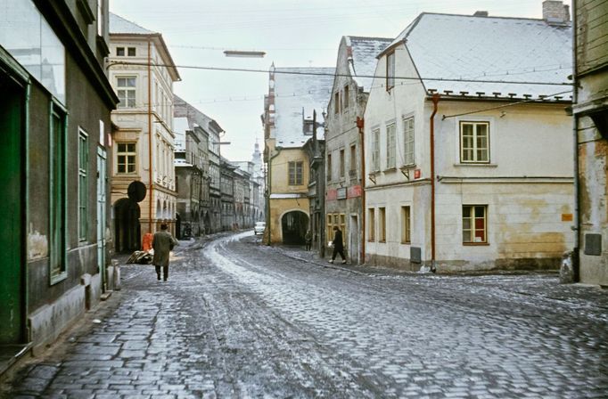 Oprýskané domy a tající sníh na dlažbě České ulice. Únor 1964.