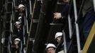 Workers watch as the forward section of the aircraft carrier HMS Queen Elizabeth is moved onto a barge at HM Naval Base in Portsmouth, southern England May 14, 2012. The hull will be transported by a sea going barge to Rosyth in Scotland where the ship will be assembled in dry dock. REUTERS/Luke MacGregor (BRITAIN - Tags: BUSINESS EMPLOYMENT MILITARY) Published: Kvě. 14, 2012, 2:30 odp.