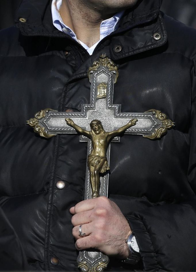 A man holds a crucifix as he stands in a packed Saint Peter's Square where Pope Benedict XVI holds his last general audience, at the Vatican February 27, 2013. The weekly event which would normally be held in a vast auditorium in winter, but has been moved outdoors to St. Peter's Square so more people can attend. The pope has two days left before he takes the historic step of becoming the first pontiff in some six centuries to step down instead of ruling for life. REUTERS/Max Rossi (VATICAN - Tags: RELIGION SOCIETY) Published: Úno. 27, 2013, 9:52 dop.