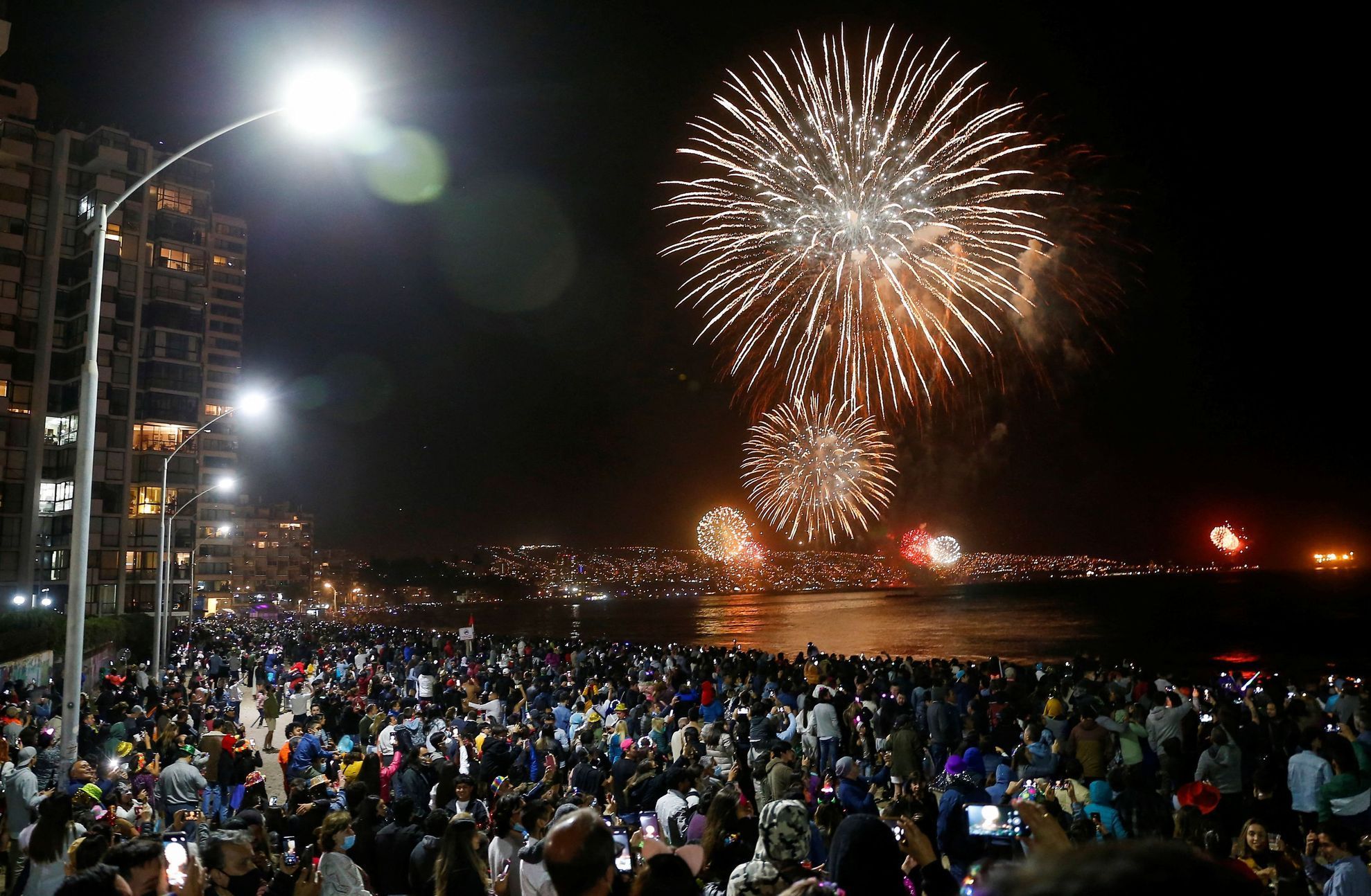 People gather to watch fireworks explode over a beach during New Year celebrations in the coastal city of Vina del Mar