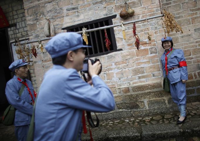 A mid-level government official dressed in red army uniform poses for a picture as she visits an old house where former Chinese leader Mao Zedong used to live during a 5-day training course at the communist party school called China Executive Leadership Academy of Jinggangshan, in Jiangxi province, in this September 21, 2012 file photo. China's Communist Party has dramatically stepped up its training of the country's roughly 40 million party and government officials in the past decade. With public scrutiny of cadre behaviour growing via social media, the party is likely to call for continued, and deepened, cadre education at the upcoming 18th Party Congress. At the vanguard of this education drive, alongside a Central Party School in Beijing, are three "Executive Leadership Academies" which opened in 2005 for middle-ranking and senior officials in Shanghai, Yan'an and Jinggangshan. The curriculum covers Marxism, Leninism and Mao Zedong Thought, but students may also take finance courses, receive in-depth media training or role-play crisis management scenarios on everything from disease outbreaks to train wrecks. REUTERS/Carlos Barria/Files (CHINA - Tags: POLITICS SOCIETY) Published: Zář. 24, 2012, 2:17 odp.