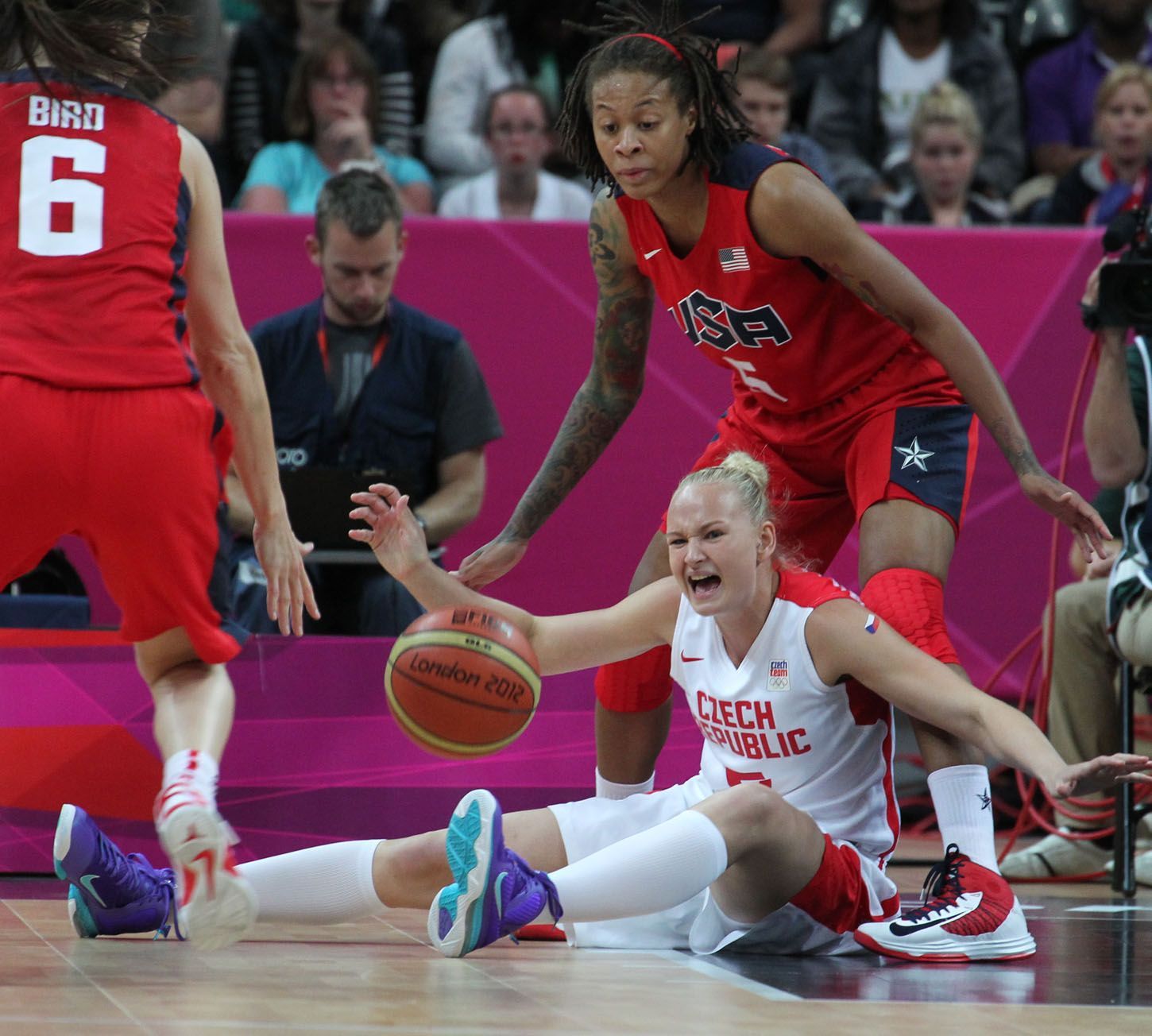 Česká basketbalistka Michaela Zrůstová se rozčiluje po pádu pod Američankou Simeone Augustusovou v utkání skupiny A na OH 2012 v Londýně.