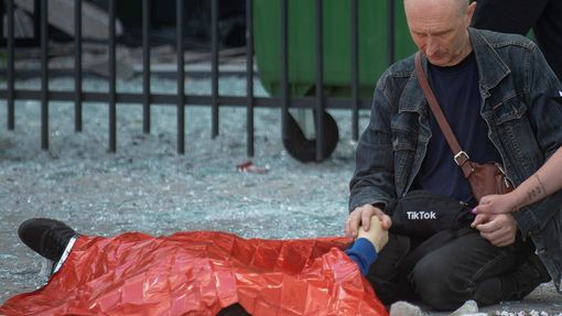 Muž drží ruku svého 13letého syna, který zemřel při ruském útoku na město Charkov.