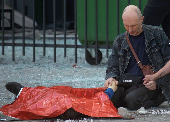 Muž drží ruku svého 13letého syna, který zemřel při ruském útoku na město Charkov.