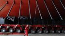 A worker passes the supports of the forward section of the aircraft carrier HMS Queen Elizabeth as it is moved onto a barge at HM Naval Base in Portsmouth, southern England May 14, 2012. The hull will be transported by a sea going barge to Rosyth in Scotland where the ship will be assembled in dry dock. REUTERS/Luke MacGregor (BRITAIN - Tags: BUSINESS EMPLOYMENT MILITARY) Published: Kvě. 14, 2012, 2:50 odp.