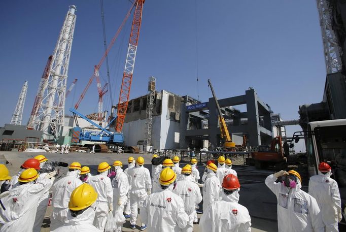 Members of the media wearing protective suits and masks are escorted by TEPCO employees as they go on a visit near the No.4 reactor (C) and its foundation construction (R) for the storage of melted fuel rods at Tokyo Electric Power Company's (TEPCO) tsunami-crippled Fukushima Daiichi nuclear power plant in Fukushima prefecture March 6, 2013, ahead of the second-year of anniversary of the disaster. Members of the media were allowed into the plant on Wednesday ahead of the second-year anniversary of the March 11, 2011 tsunami and earthquake, which triggered the world's worst nuclear crisis since Chernobyl. REUTERS/Issei Kato (JAPAN - Tags: DISASTER ANNIVERSARY) Published: Bře. 6, 2013, 11:24 dop.