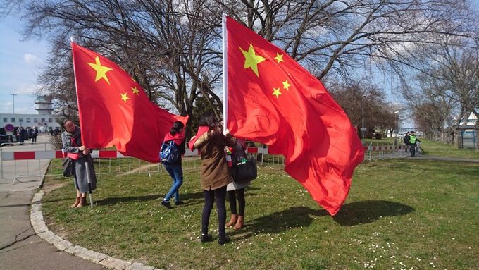 Číňané s vlajkami očekávající přílet čínského prezidenta u pražského letiště.