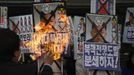 An activist from an anti-North Korea civic group burns a portrait of North's leader Kim Jong-un during a rally against North Korea's nuclear test near the U.S. embassy in central Seoul February 12, 2013. North Korea conducted its third nuclear test on Tuesday in defiance of U.N. resolutions, angering the United States and Japan and prompting its only major ally, China, to call for calm. The poster (front R) reads, "Let's pulverize North Korea's nuclear war provocations!" REUTERS/Kim Hong-Ji (SOUTH KOREA - Tags: CIVIL UNREST POLITICS TPX IMAGES OF THE DAY) Published: Úno. 12, 2013, 9:07 dop.