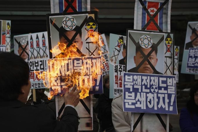 An activist from an anti-North Korea civic group burns a portrait of North's leader Kim Jong-un during a rally against North Korea's nuclear test near the U.S. embassy in central Seoul February 12, 2013. North Korea conducted its third nuclear test on Tuesday in defiance of U.N. resolutions, angering the United States and Japan and prompting its only major ally, China, to call for calm. The poster (front R) reads, "Let's pulverize North Korea's nuclear war provocations!" REUTERS/Kim Hong-Ji (SOUTH KOREA - Tags: CIVIL UNREST POLITICS TPX IMAGES OF THE DAY) Published: Úno. 12, 2013, 9:07 dop.