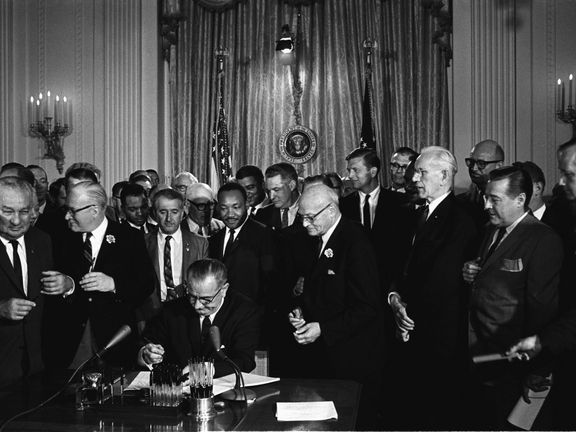 Prezident Johnson podepisuje v roce 1964 Zákon o občanských právech (Luther King za ním).