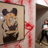 Woman walks past &quot;Kissing Coppers&quot; by artist Banksy at Banksy: The Unauthorised Retrospective at Sotheby's S2 Gallery in London June 06, 2014. REUTERS/Neil Hall (BRITAIN)
