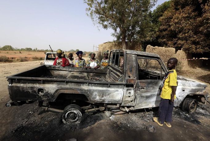 A boy and a group of women stand near a vehicle, believed to belong to Islamist rebels and destroyed during French air strikes, in the recently liberated town of Diabaly January 24, 2013. REUTERS/Eric Gaillard (MALI - Tags: CIVIL UNREST CONFLICT MILITARY POLITICS) Published: Led. 24, 2013, 6 odp.