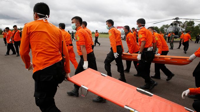 Indonéský tým vyšetřovatelů míří k helikoptéře, která přivezla první těla obětí leteckého neštěstí.