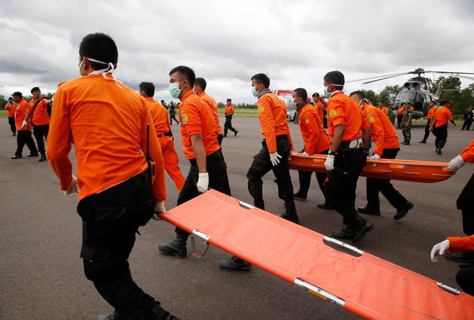 Indonéský tým vyšetřovatelů míří k helikoptéře, která přivezla první těla obětí leteckého neštěstí.