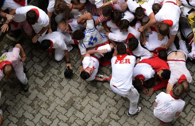 Runners fall down and form a "Montonera" (Many People) at the entrance to the bullring during the first running of the bulls of the San Fermin festival in Pamplona July 7, 2012. One person was gored and four others injured in a run by Dolores Aguirre fighting bulls that lasted two minutes and fifty-two seconds, according to local media. REUTERS/Vincent West (SPAIN - Tags: ANIMALS SOCIETY) Published: Čec. 7, 2012, 9:13 dop.