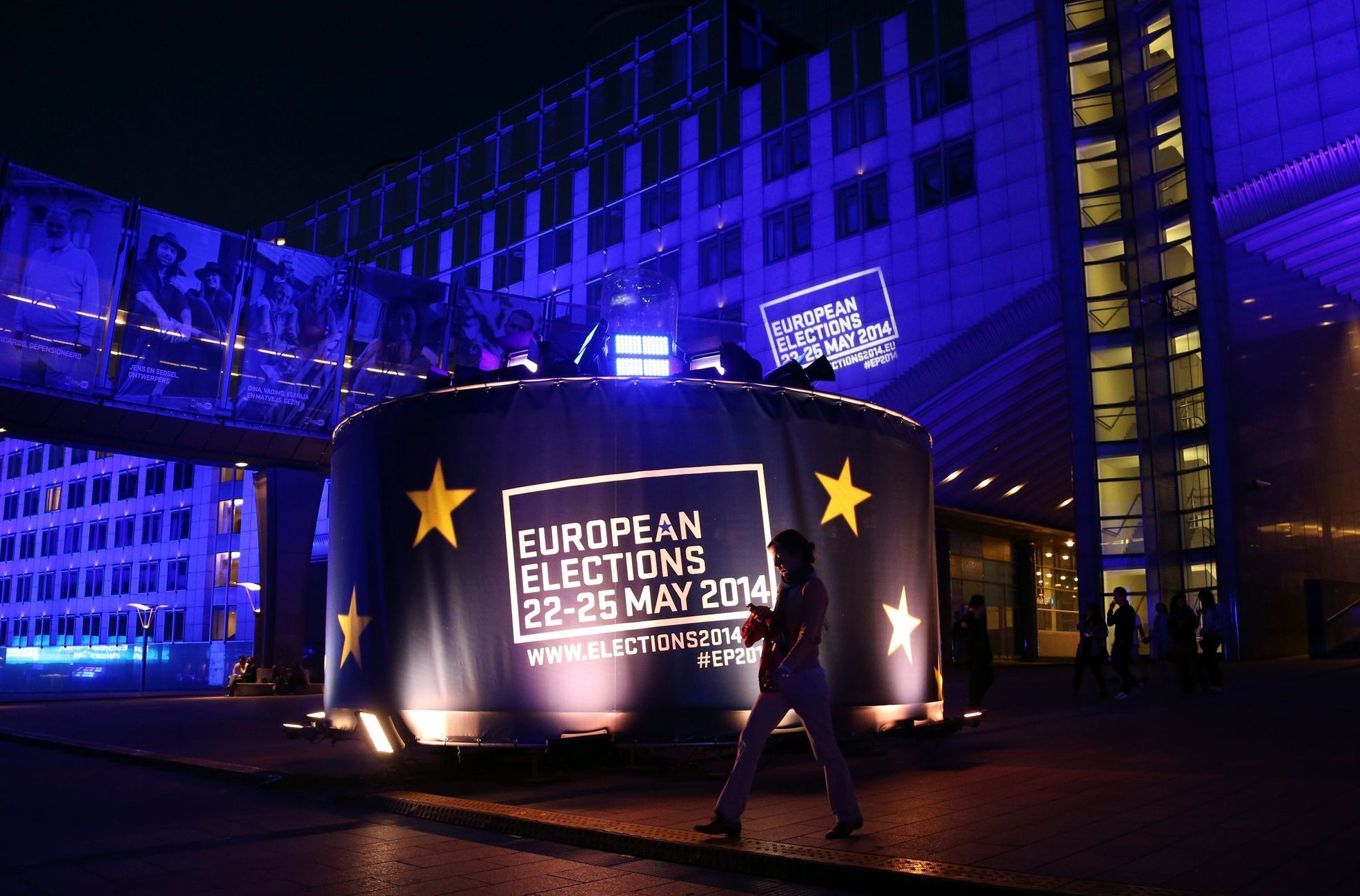 A woman walks past a banner promoting the European elections in front of the European Parliament in Brussels