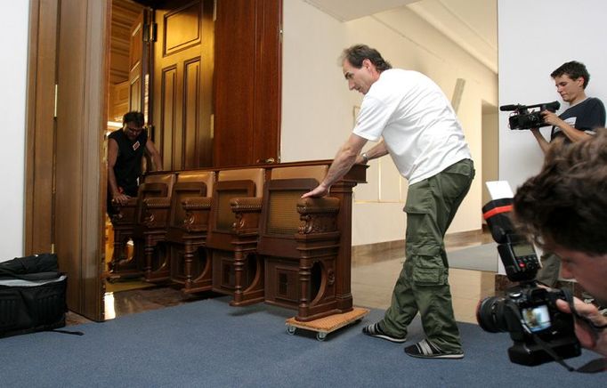 Lavice, hejbejte se. Na kolečkách opouštějí poslanecké lavice jednací sál. Tato sedadla patřila poslancům KSČM.