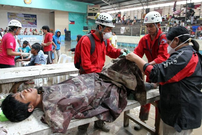 Members of the Philippine National Red Cross apply first aid to a man who survived a flash flood after Typhoon Bopha hit New Bataan in Compostela province, southern Philippines December 5, 2012. Bopha, the Philippines' strongest typhoon this year, was headed towards tourist destinations on Wednesday after hitting a southern island, destroying homes, causing landslides and killing at least 82 people, but many more are reported dead and missing. REUTERS/Stringer (PHILIPPINES - Tags: DISASTER ENVIRONMENT) Published: Pro. 5, 2012, 6:25 dop.