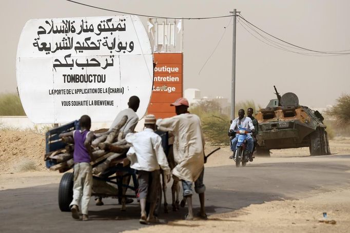 People drive past a road sign written by Islamist rebels at the entrance into Timbuktu January 31, 2013. Mali's president offered Tuareg rebels talks on Thursday in a bid for national reconciliation after a French-led offensive drove their Islamist former allies into mountain hideaways. The sign reads, "The gate of the application of sharia law welcomes you." REUTERS/Benoit Tessier (MALI - Tags: POLITICS CIVIL UNREST CONFLICT MILITARY) Published: Led. 31, 2013, 7:35 odp.