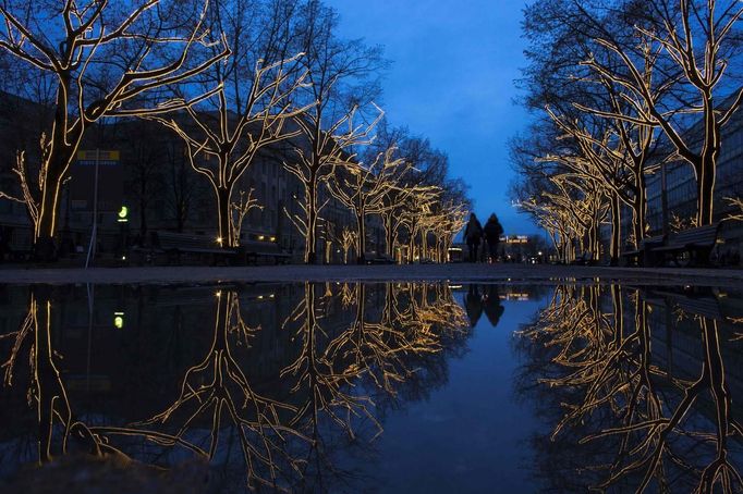 Trees decorated with Christmas lights are reflected in a puddle as people walk along the Unter den Linden promenade in Berlin November 28, 2012. REUTERS/Thomas Peter (GERMANY - Tags: SOCIETY ENVIRONMENT TPX IMAGES OF THE DAY) Published: Lis. 28, 2012, 3:48 odp.