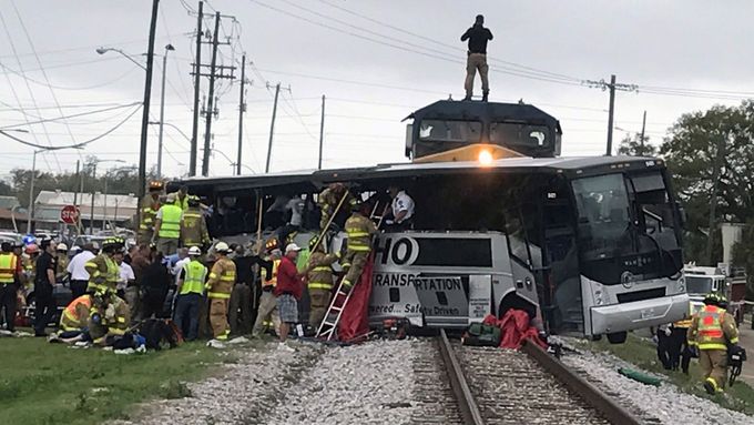 Hasiči pomáhají cestujícím po srážce vlaku s autobusem v americkém Biloxi.