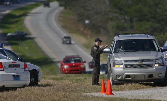 A Dale County Alabama Sheriff's deputy talks to a driver at a roadblock near the scene of a shooting and hostage taking near Midland City, Alabama February 1, 2013. Residents in a rural Alabama town prayed on Friday and called for the release of a 5-year-old boy being held captive for a fourth day by a man accused of shooting a school bus driver and then taking the child hostage. REUTERS/Phil Sears (UNITED STATES - Tags: CRIME LAW) Published: Úno. 1, 2013, 9:33 odp.