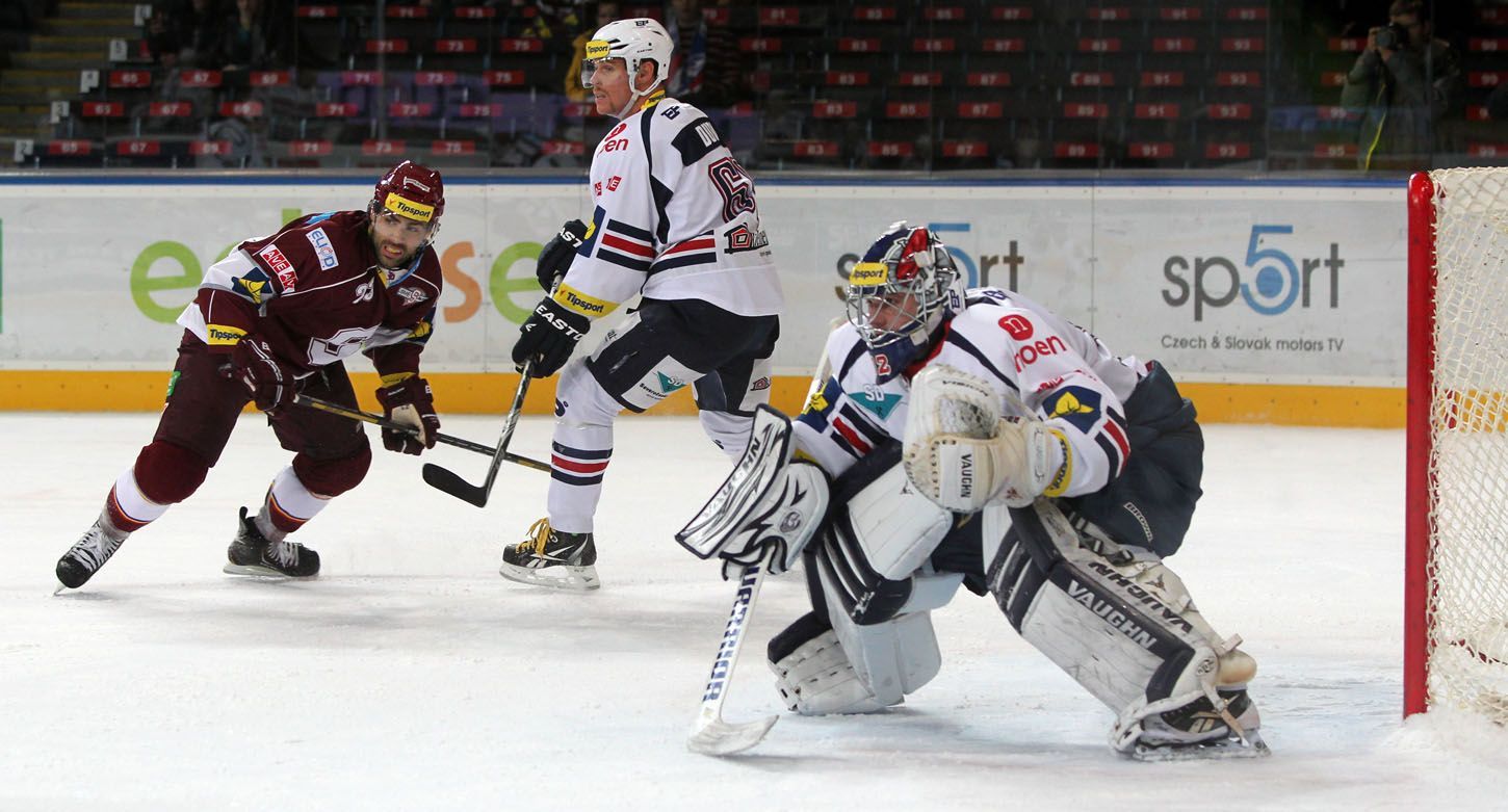 Hokejový brankář Chomutova Milan Řehoř (brankář) dává pozor. Před ním najíždí Angel Krstev v utkání 16. kola Tipsport extraligy 2012/13 proti Spartě Praha.