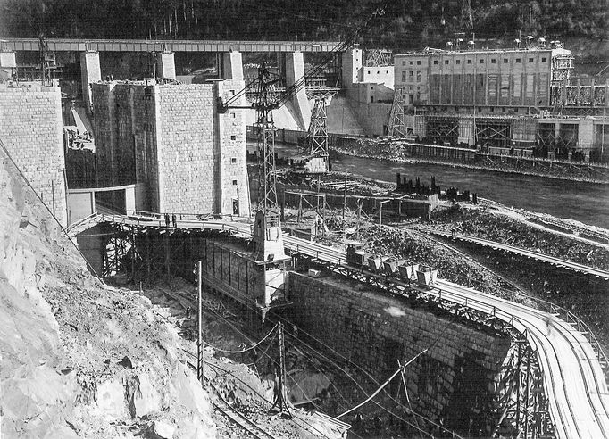 Historická fotografie zachycující výstavbu vodní nádrže Štěchovice, která probíhala mezi lety 1937 a 1944, navzdory válečným komplikacím.