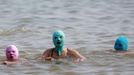 Women, wearing nylon masks, swim in the water during their visit to a beach in Qingdao, Shandong province July 6, 2012. The mask, which was invented by a woman about seven years ago, is used to block the sun's rays. The mask is under mass production and is on sale at local swimwear stores. REUTERS/Aly Song (CHINA - Tags: SOCIETY TRAVEL ENVIRONMENT TPX IMAGES OF THE DAY) Published: Čec. 6, 2012, 6:56 odp.