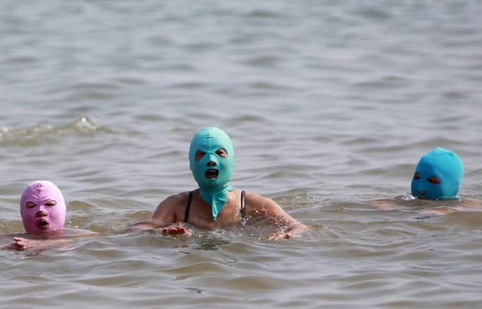 Women, wearing nylon masks, swim in the water during their visit to a beach in Qingdao, Shandong province July 6, 2012. The mask, which was invented by a woman about seven years ago, is used to block the sun's rays. The mask is under mass production and is on sale at local swimwear stores. REUTERS/Aly Song (CHINA - Tags: SOCIETY TRAVEL ENVIRONMENT TPX IMAGES OF THE DAY) Published: Čec. 6, 2012, 6:56 odp.